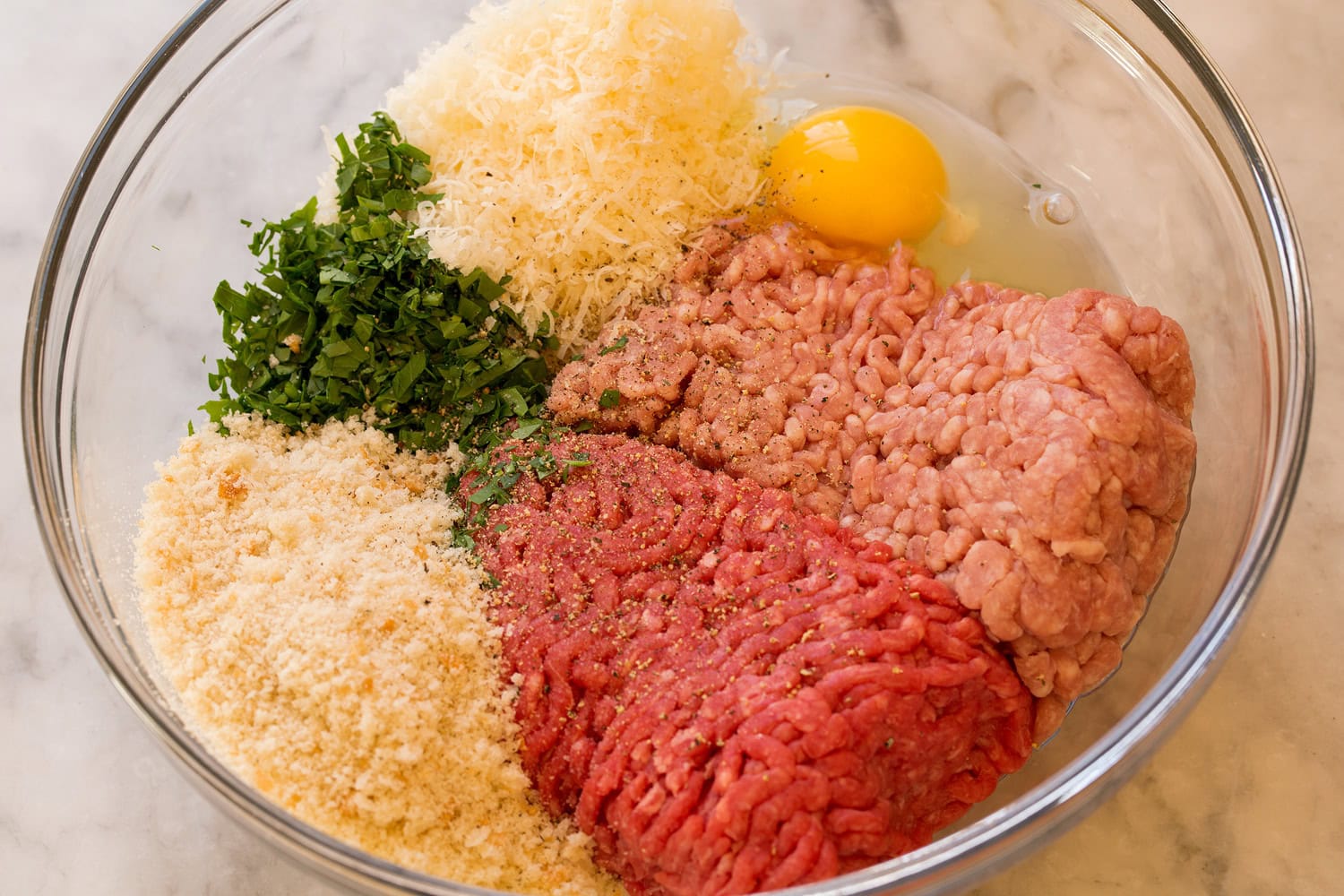 Italian Wedding Soup Ground beef, pork, herbs, parmesan, egg and breadcrumbs in a mixing bowl.