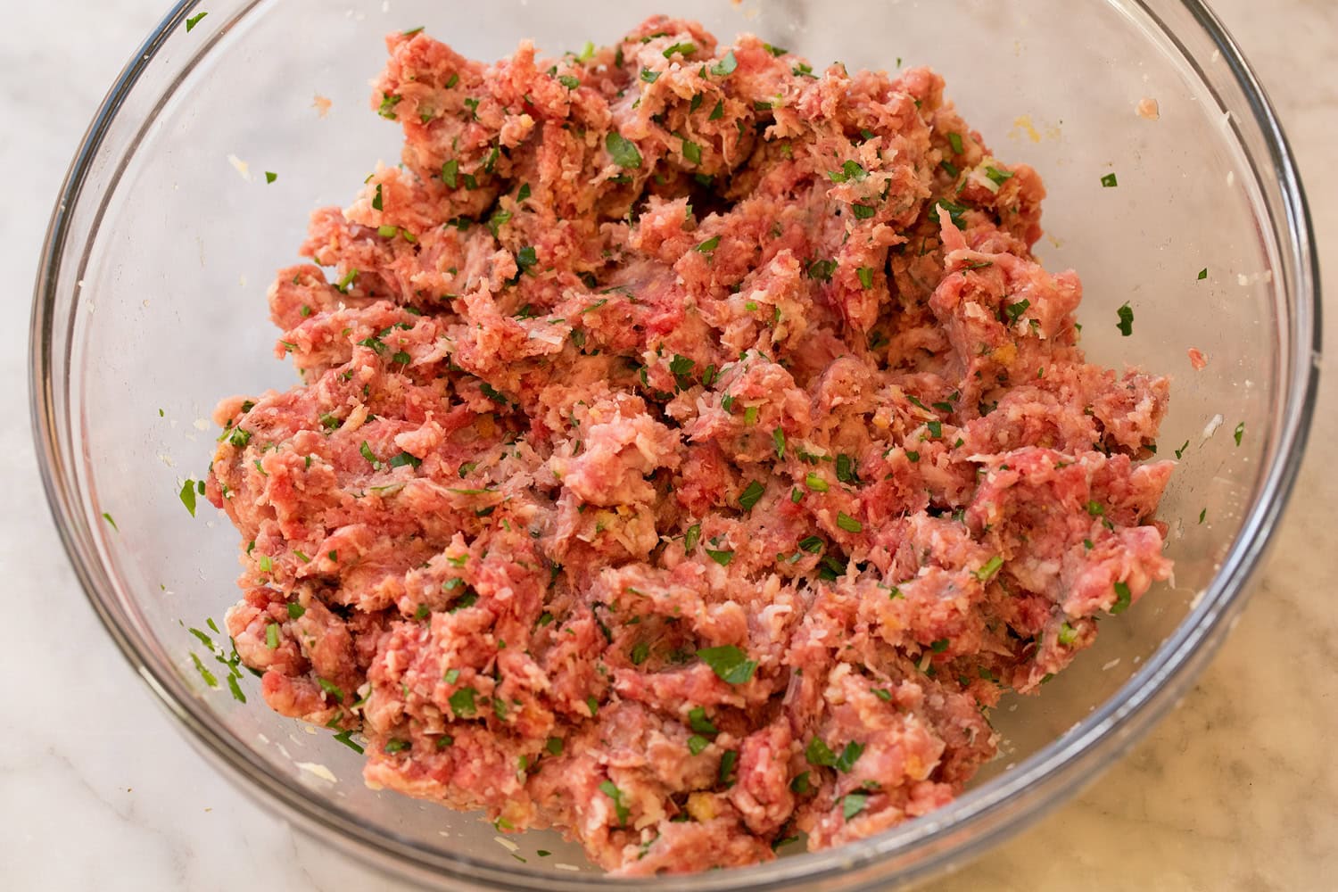 Italian Wedding Soup Meatball mixture in glass mixing bowl shown after mixing.