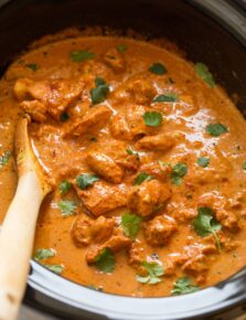 Slow cooker chicken tikka masala garnished with cilantro in a black crockpot.