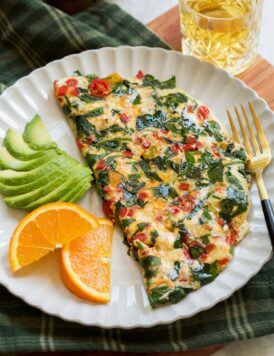 Healthy egg white omelette served with avocado slices and sliced oranges.