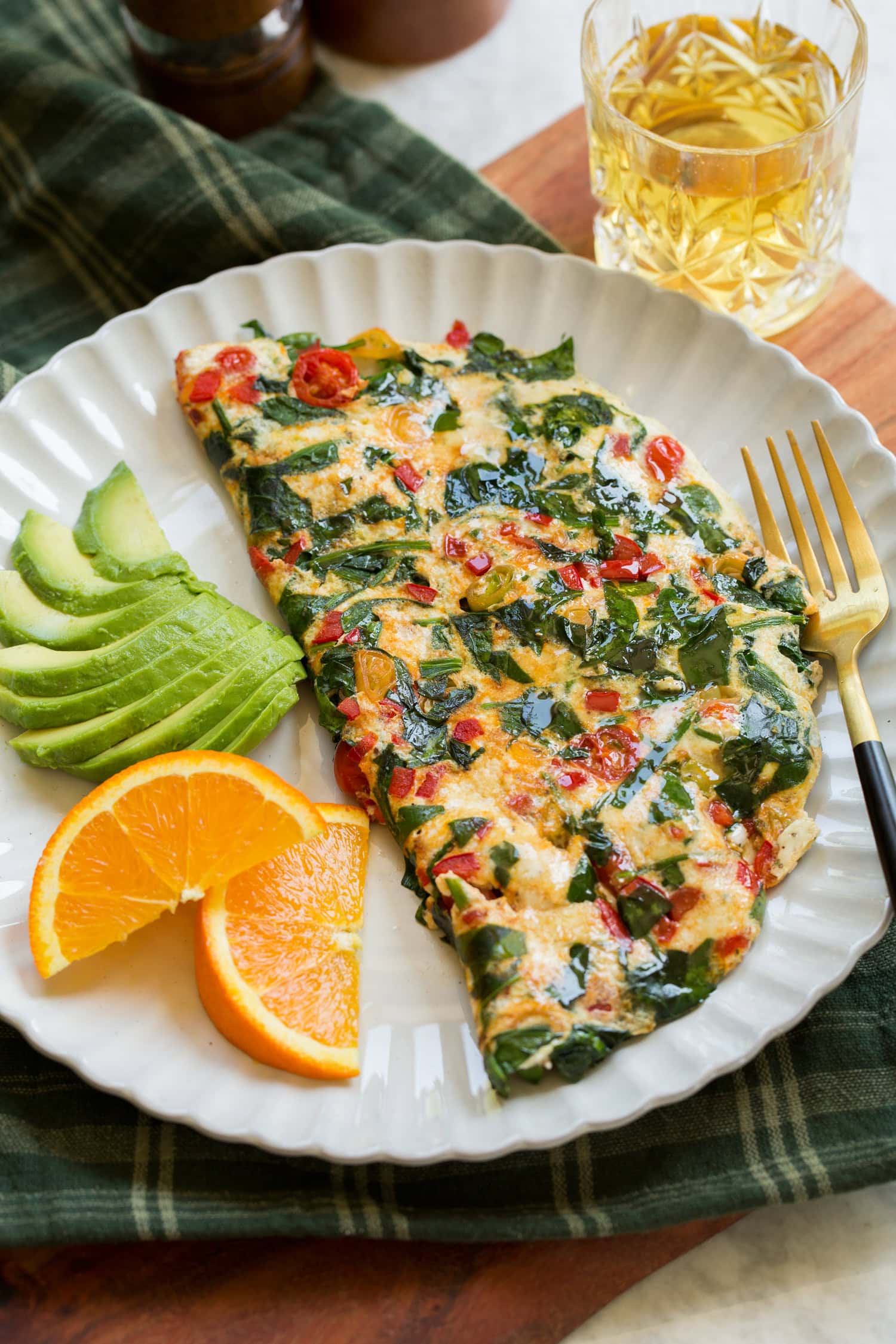 Healthy egg white omelette served with avocado slices and sliced oranges.