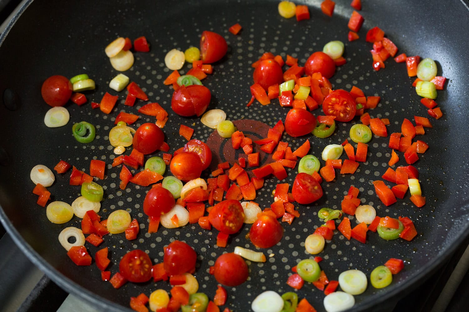 Egg White Omelette Bell pepper, tomatoes and green onions being sauteed in a skillet.