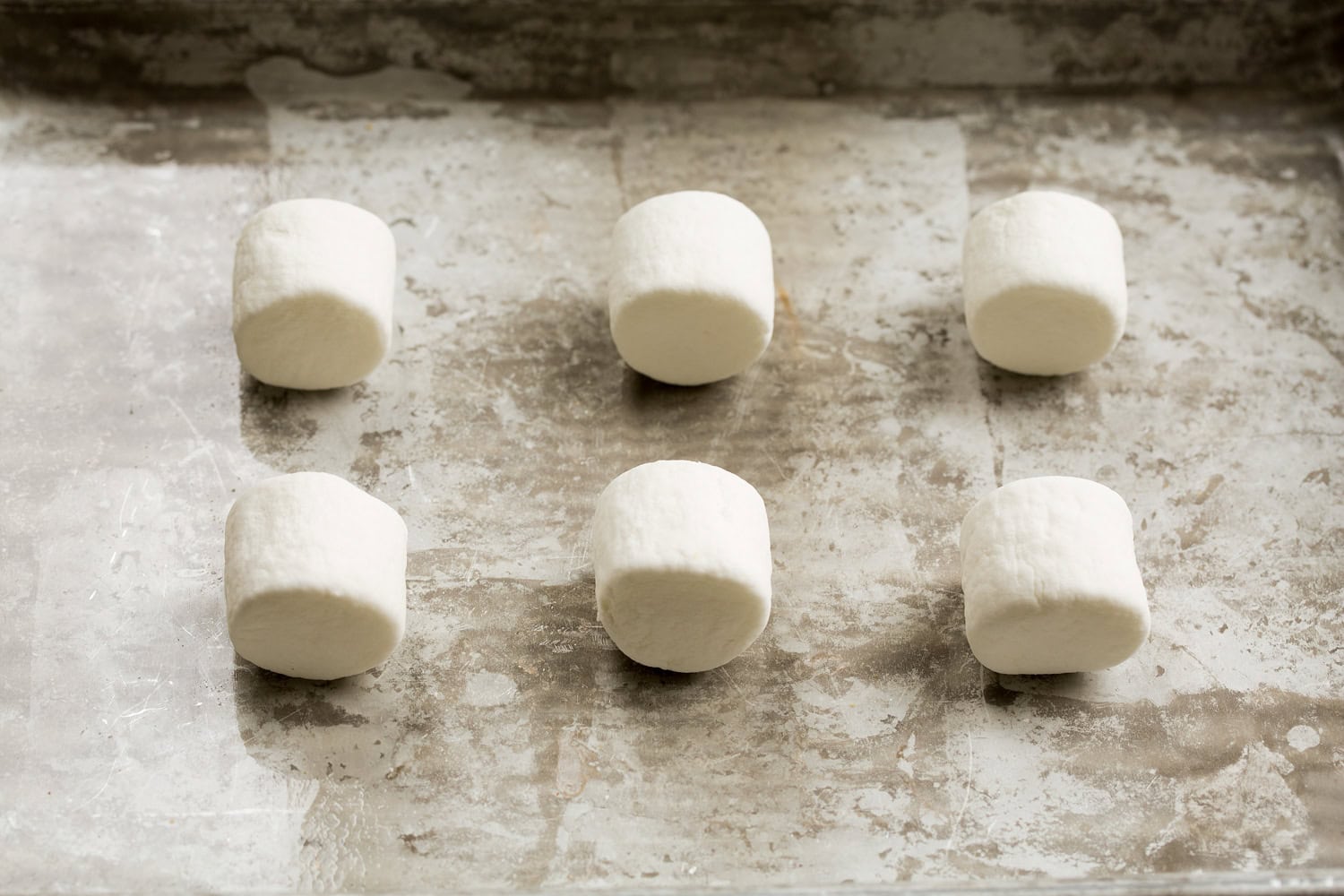 Oven S'mores Plain untoasted marshmallows on a baking sheet.