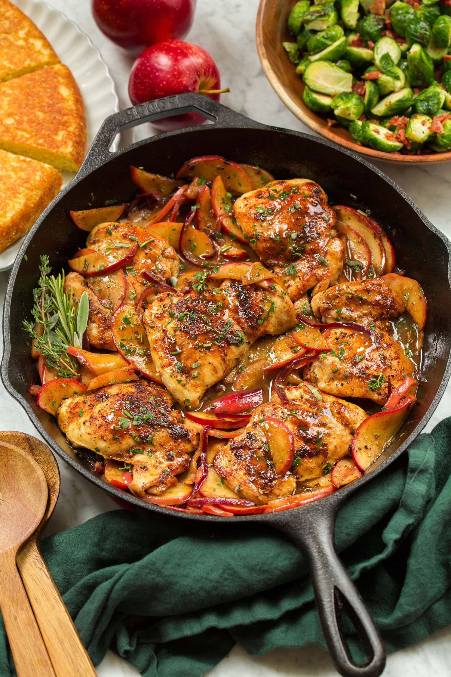 Apple Chicken Chicken and apples layered together in cast iron skillet with herb garnish.