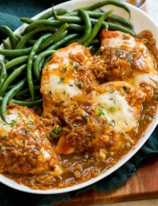 French onion chicken served on a white platter with green beans.