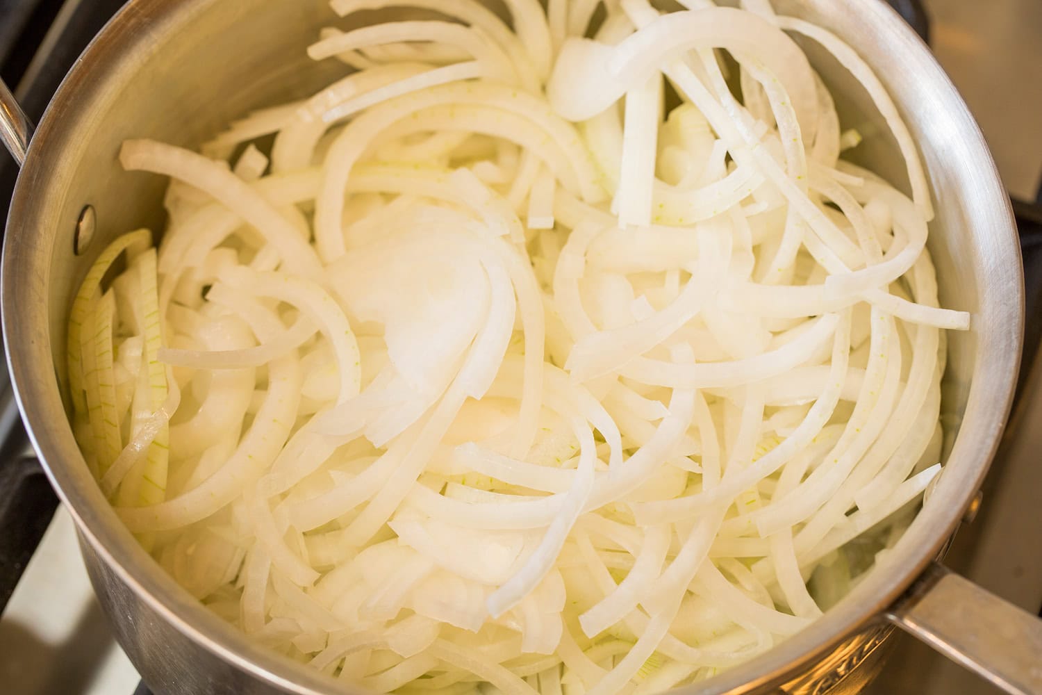 French Onion Chicken Sliced onions in saucepan shown raw.