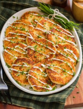 Potato cakes on a white oval platter over a green gingham cloth.