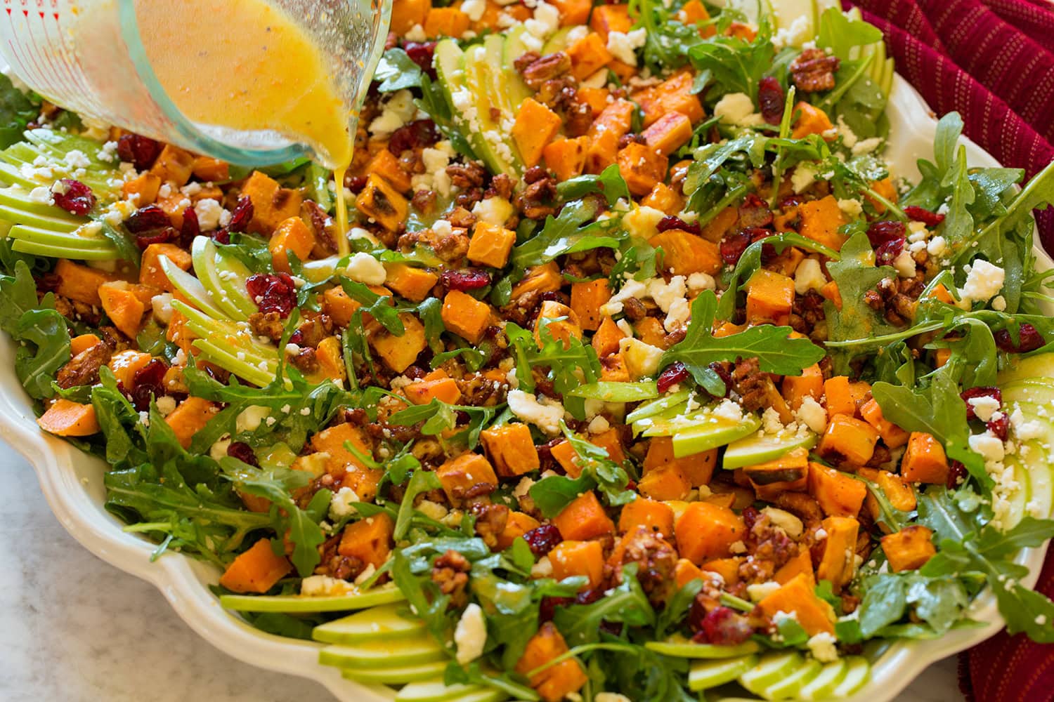 Sweet Potato Salad Drizzling dressing over prepared sweet potato salad.