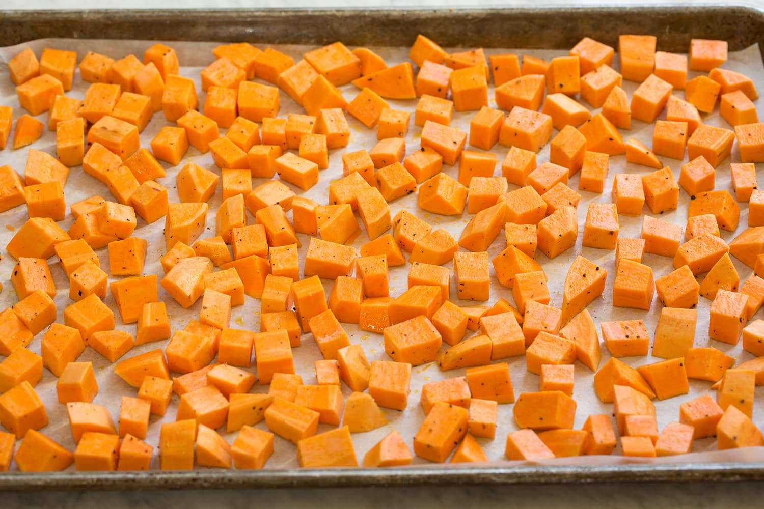 Sweet Potato Salad Raw chopped sweet potatoes shown on baking sheet before roasting.