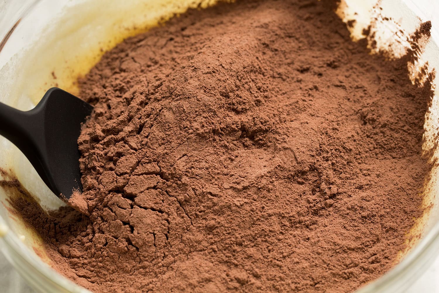 Adding flour cocoa mixture into egg, butter, sugar mixture.