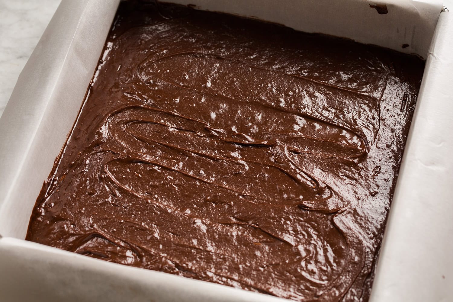 Brownie batter spread into a metal baking dish.