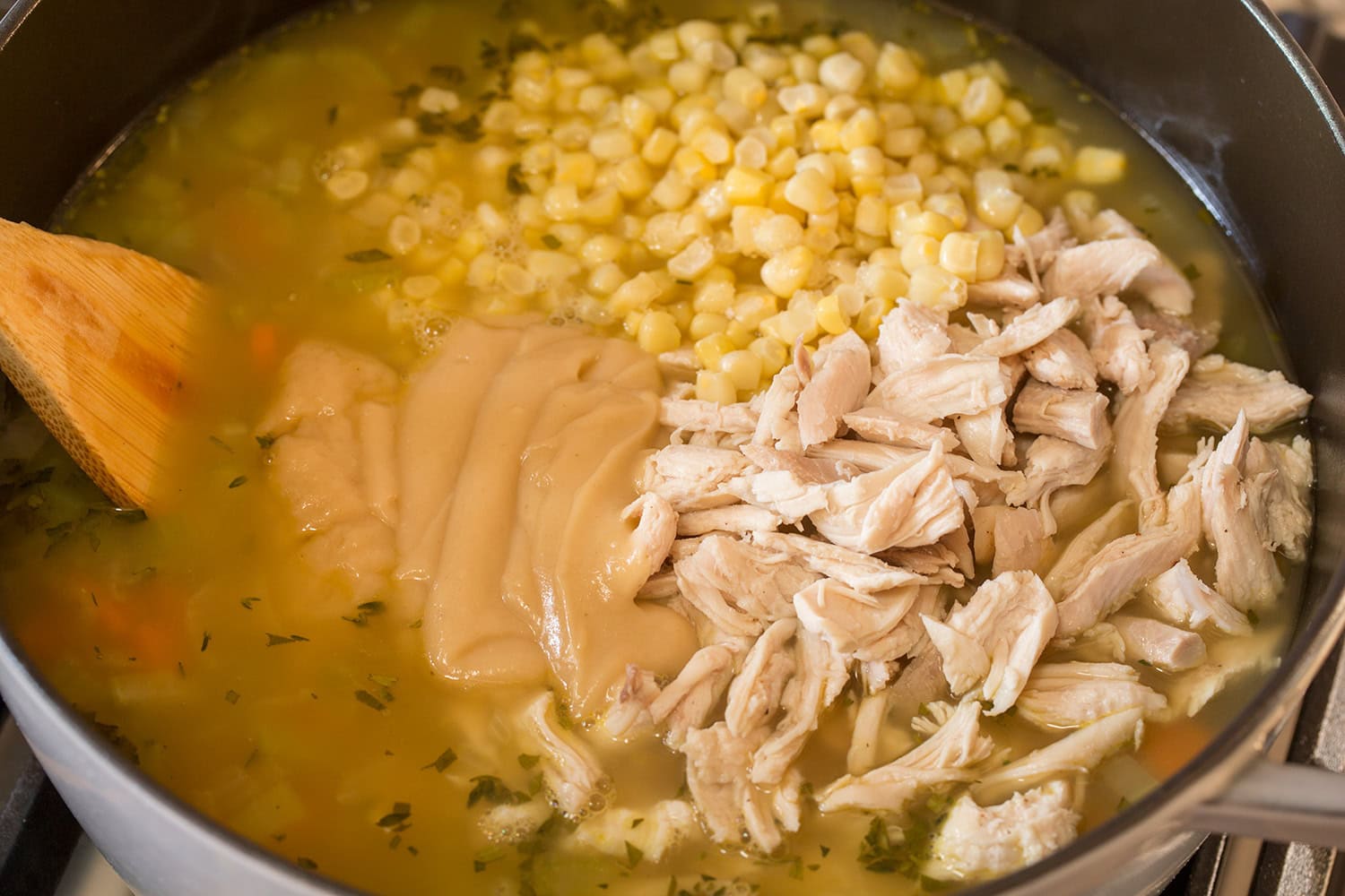 Turkey Soup Corn, leftover turkey, and gravy added to soup in pot.
