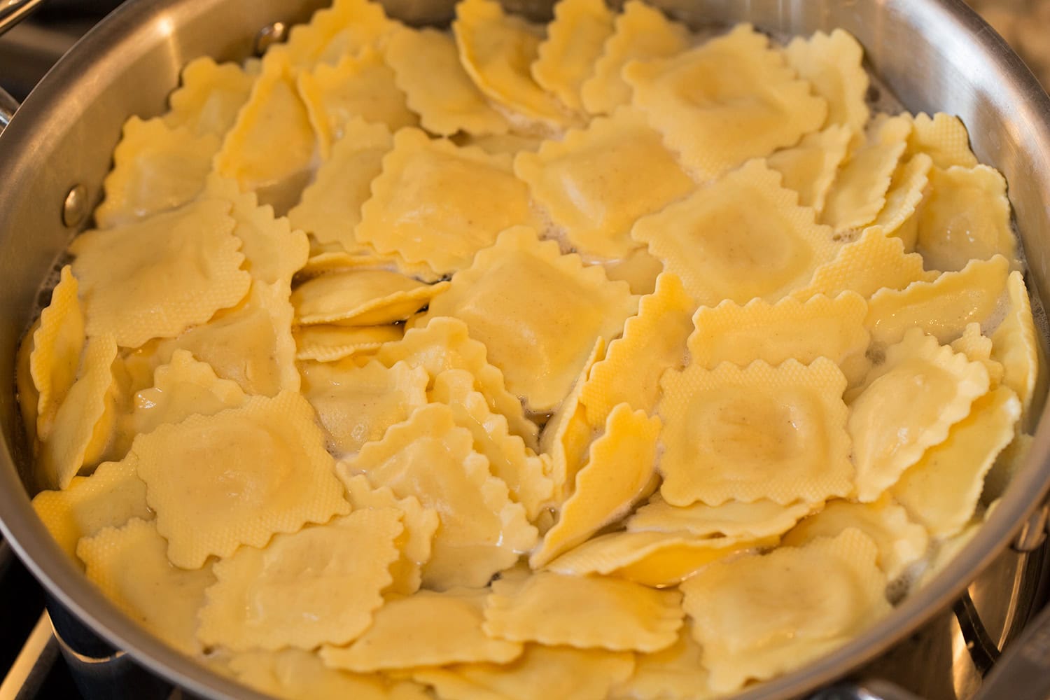 Ravioli cooking in a large pot of boiling water.