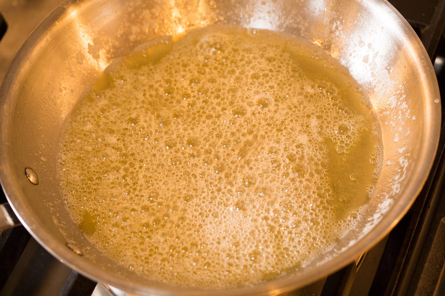 Melted butter shown a yellow shade in a skillet, first stage of melting and browning.