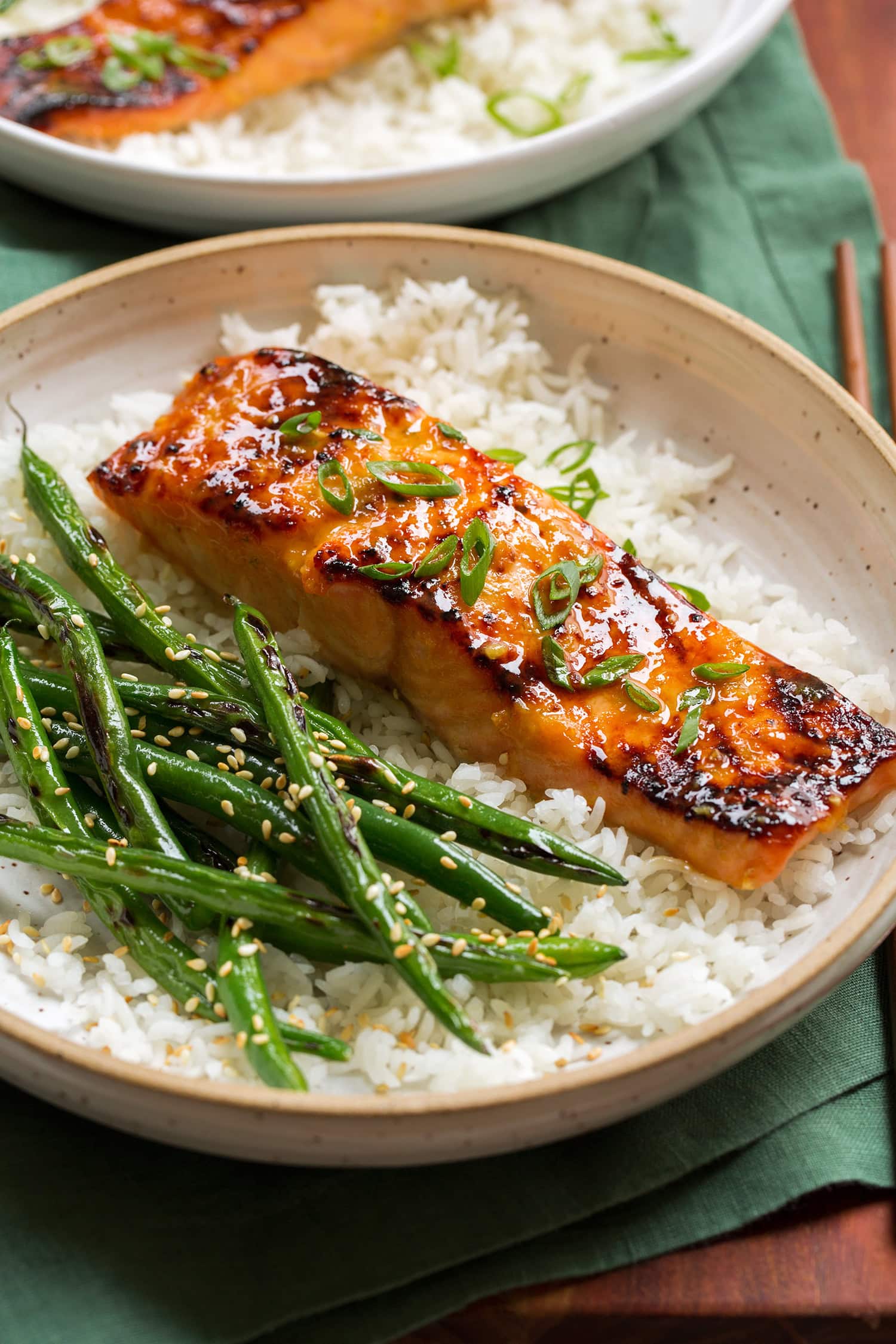 Close up of miso salmon garnished with green onions served over white rice with green beans on the side.