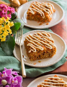 Two slices of carrot cake baked oatmeal covered in a cream cheese icing.