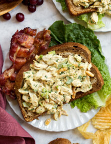 Honey mustard chicken salad shown on a slice of rye bread with bacon and lettuce to the side.