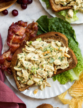 Honey mustard chicken salad shown on a slice of rye bread with bacon and lettuce to the side.