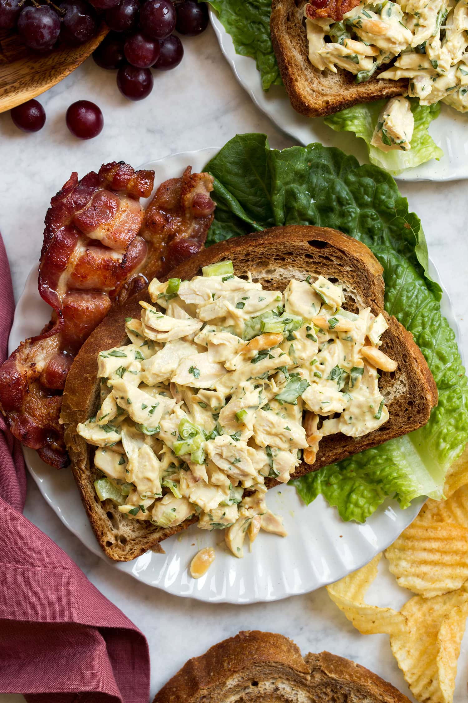 Honey mustard chicken salad shown on a slice of rye bread with bacon and lettuce to the side.