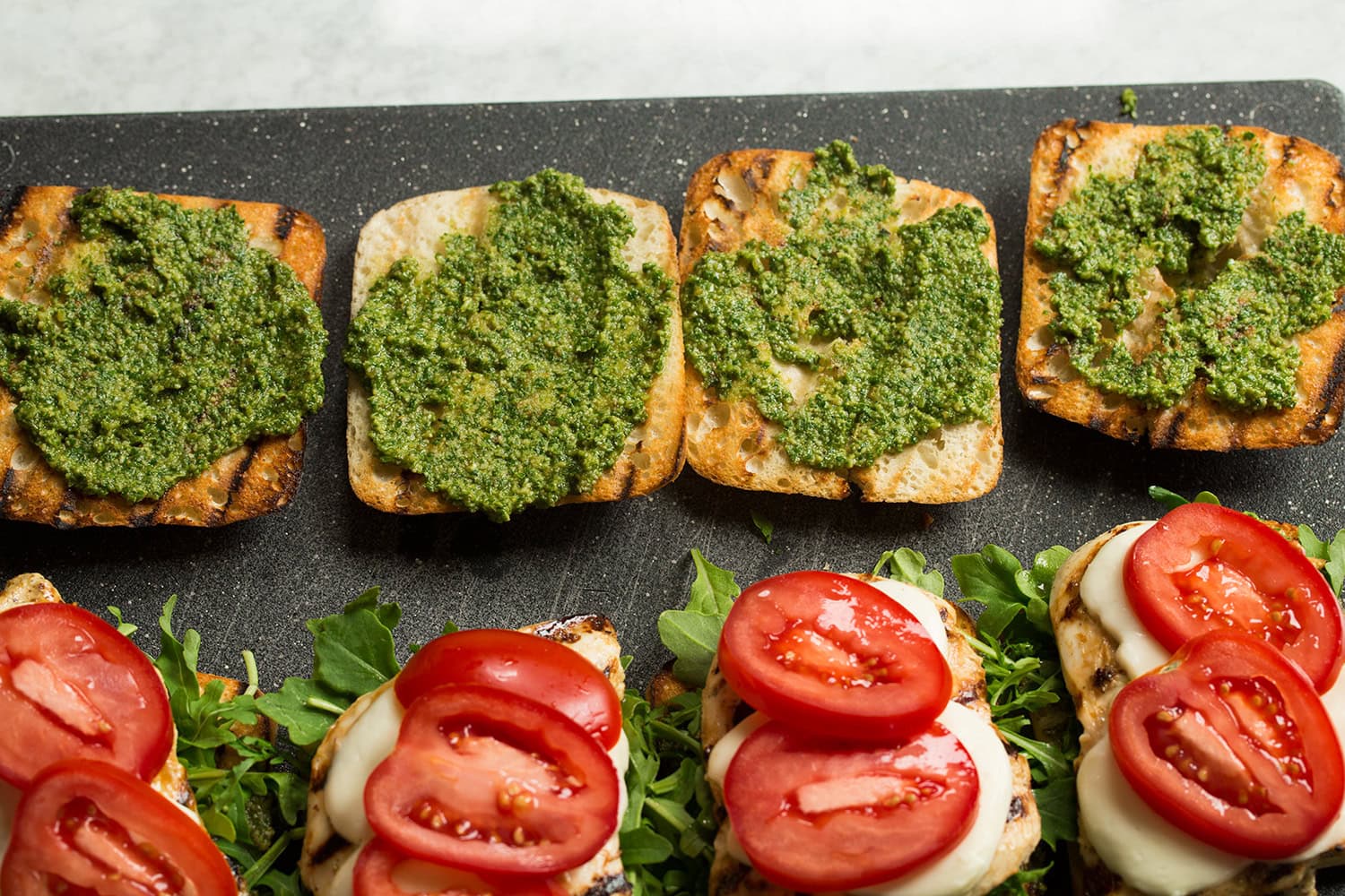 Second side of ciabatta roll covered in pesto.