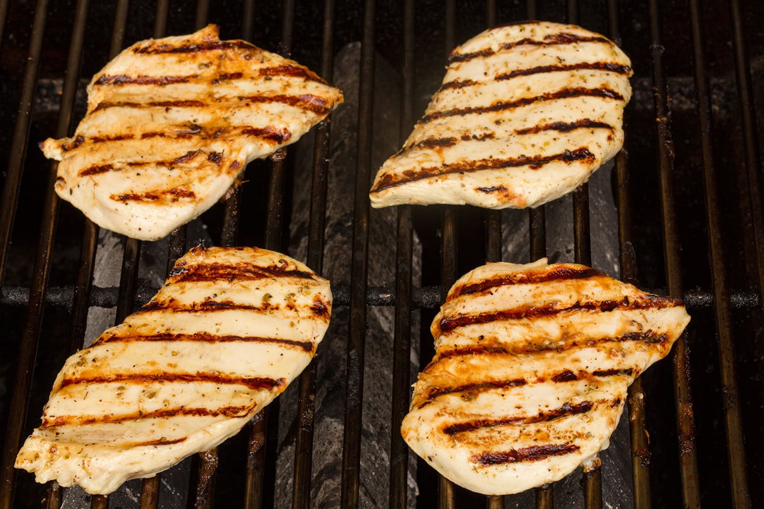 Grilled chicken breasts after turning from first side, showing grill marks.