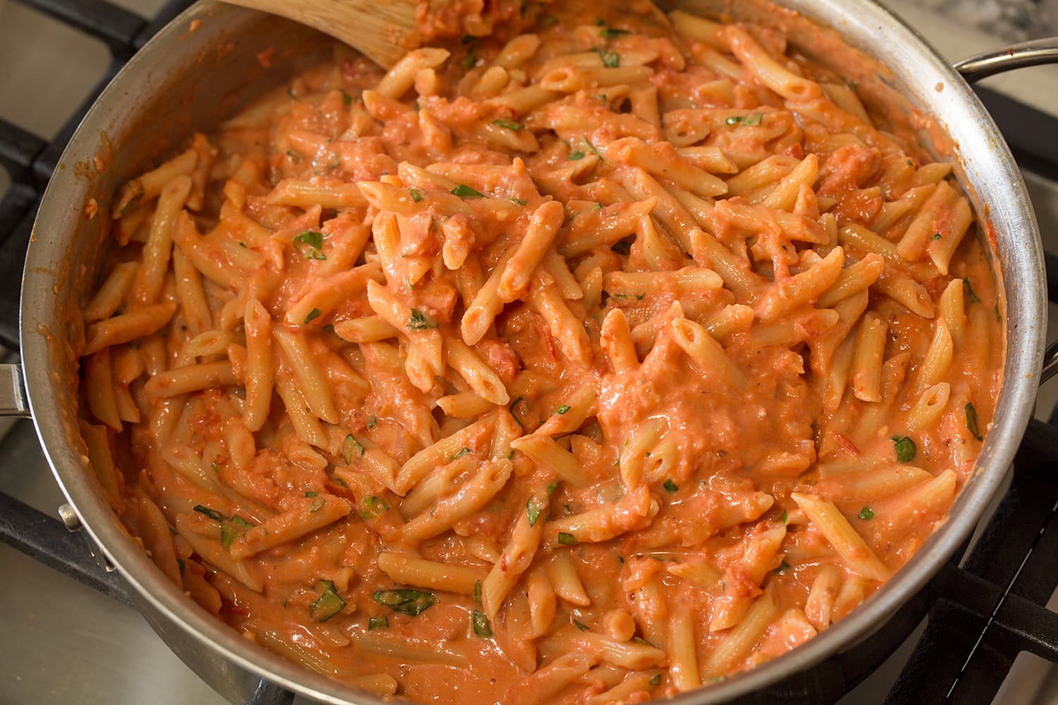 Completed creamy tomato pasta shown in a saute pan.