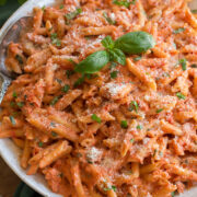 Close up photo of creamy tomato pasta. Shown on penne pasta with basil and parmesan garnish.