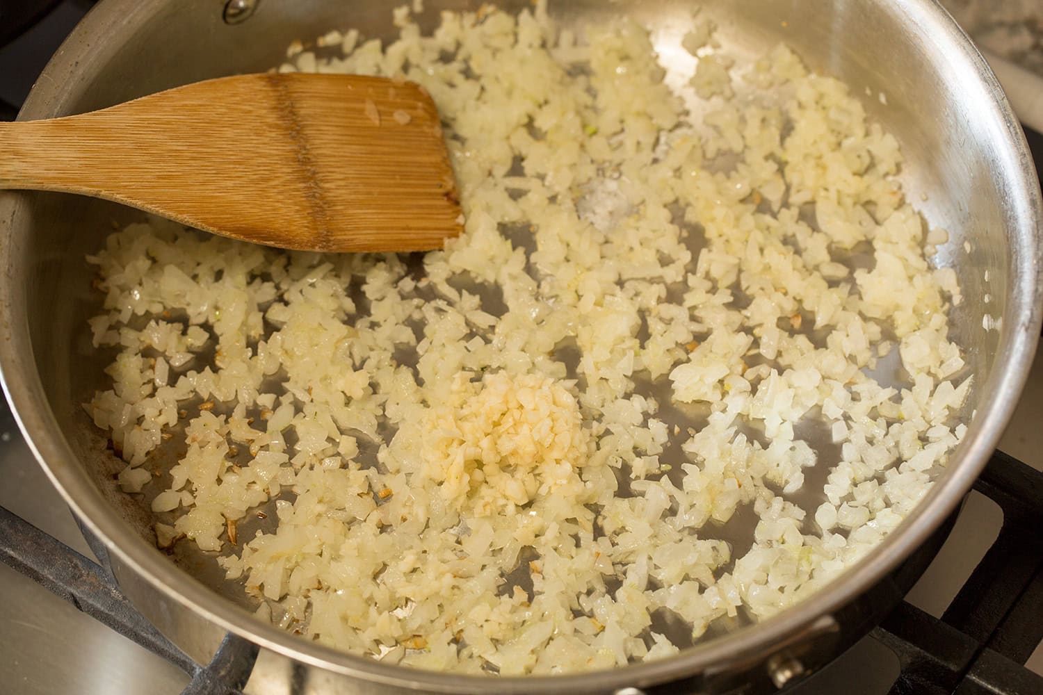 Sauteing onions and garlic in a stainless steel saute pan.