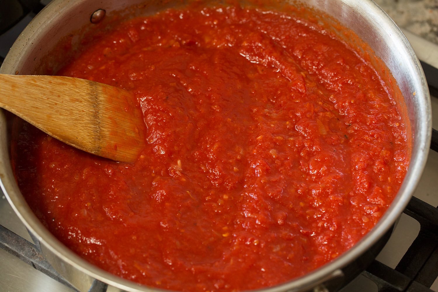 Crushed tomatoes added to saute pan.