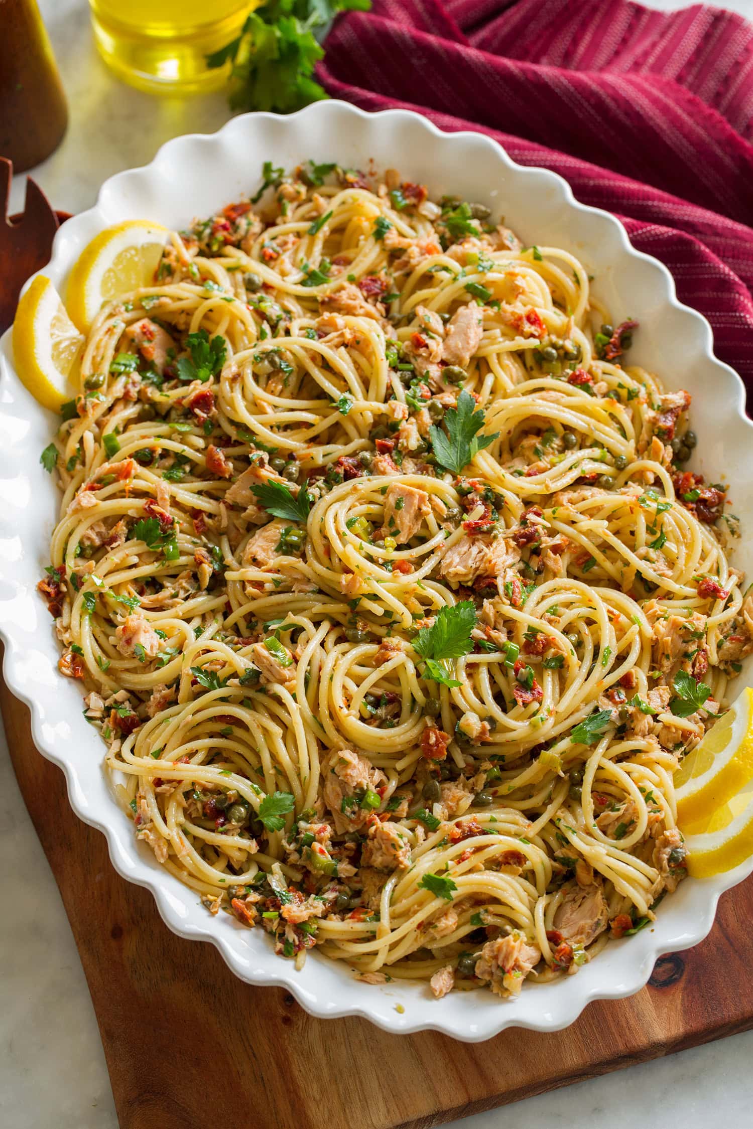Tuna spaghetti in a white serving bowl on a decorative wooden serving tray.