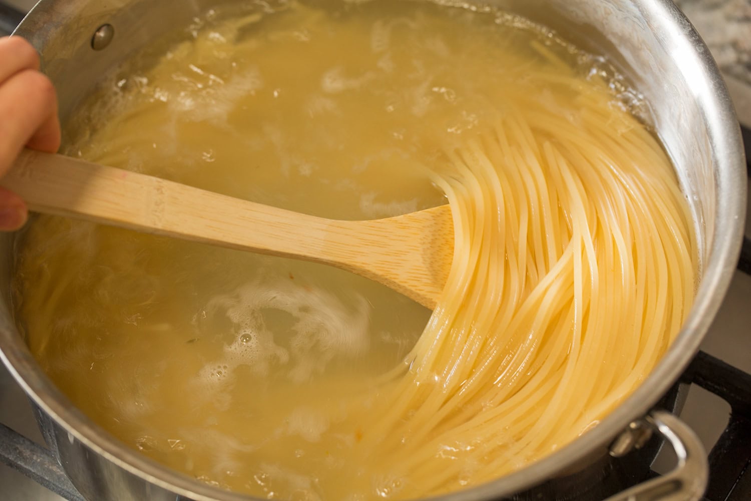 Spaghetti shown boiled to all dente in a pot of boiling water.