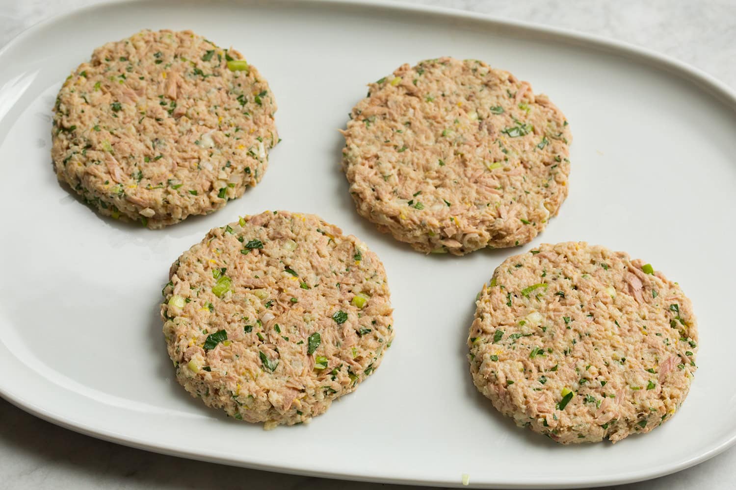 Tuna patties shown shaped into four equal portions, raw.